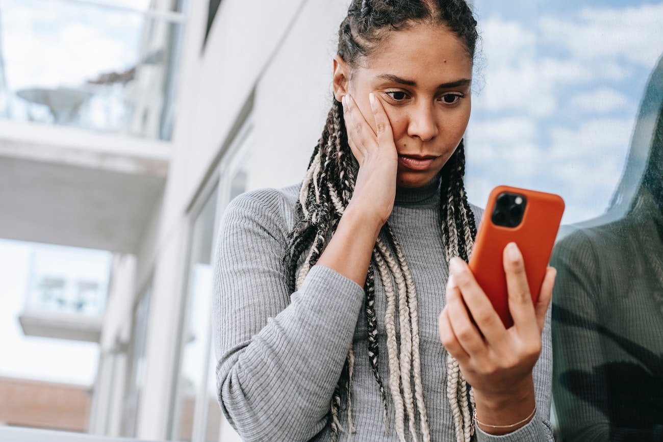 Woman looking unhappy as she looks down at her phone 
