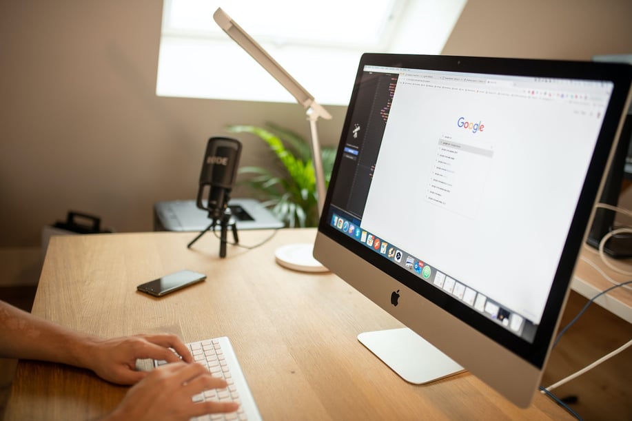 computer monitor on a desk that is opened up to google with a person typing on the keyboard