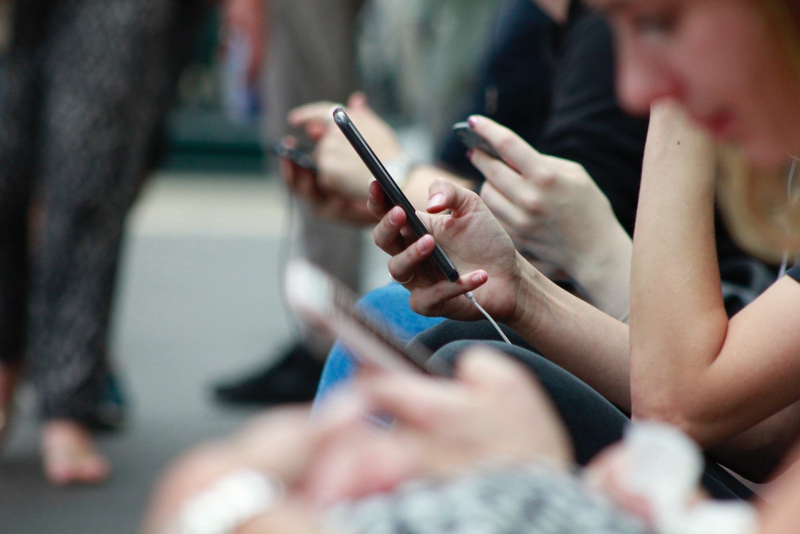 People taking public transportation all seated beside each other staring into their mobile devices