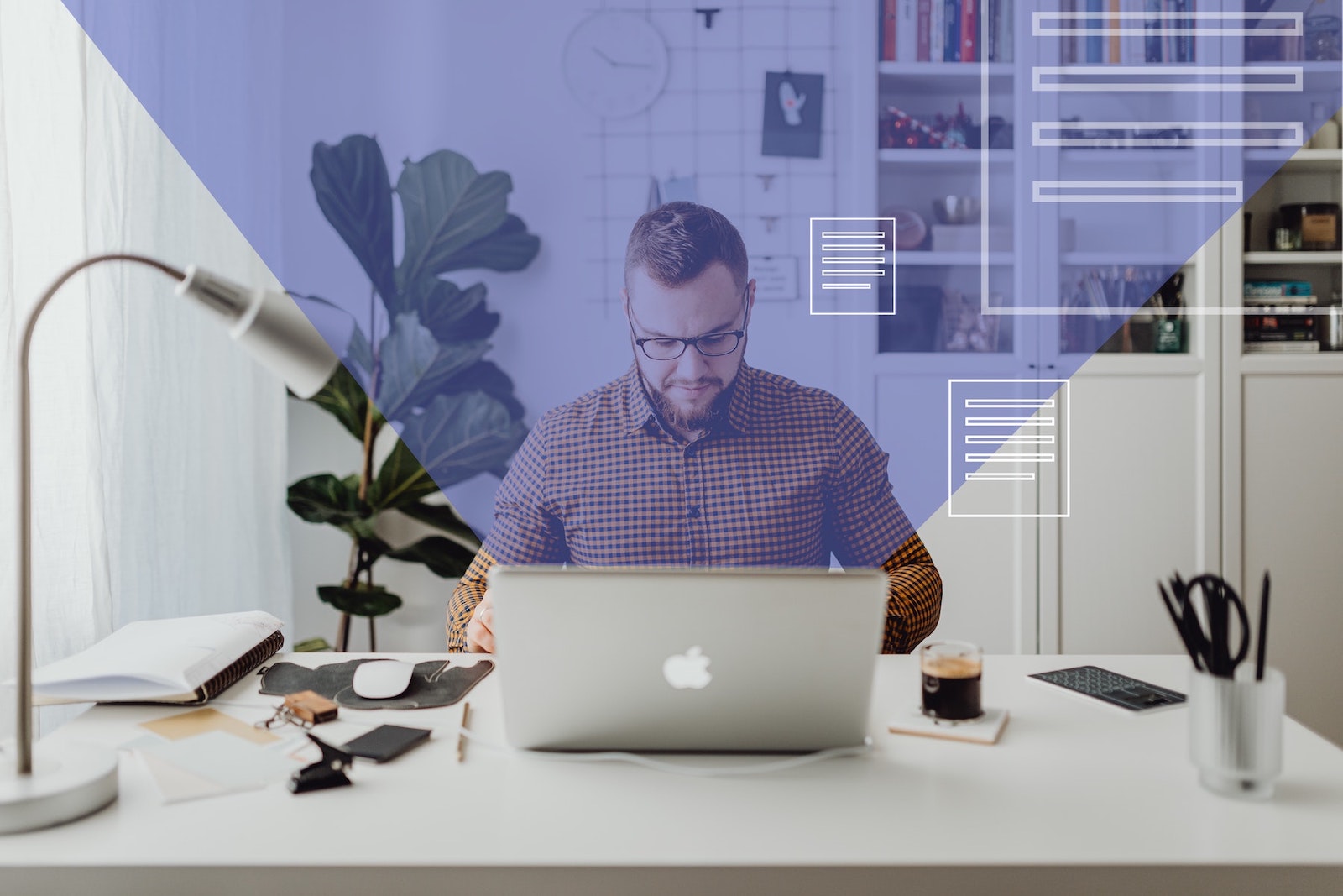 man in a plaid shirt sitting at a desk looking down at his computer with a purple graphic overlay coming out of the screen